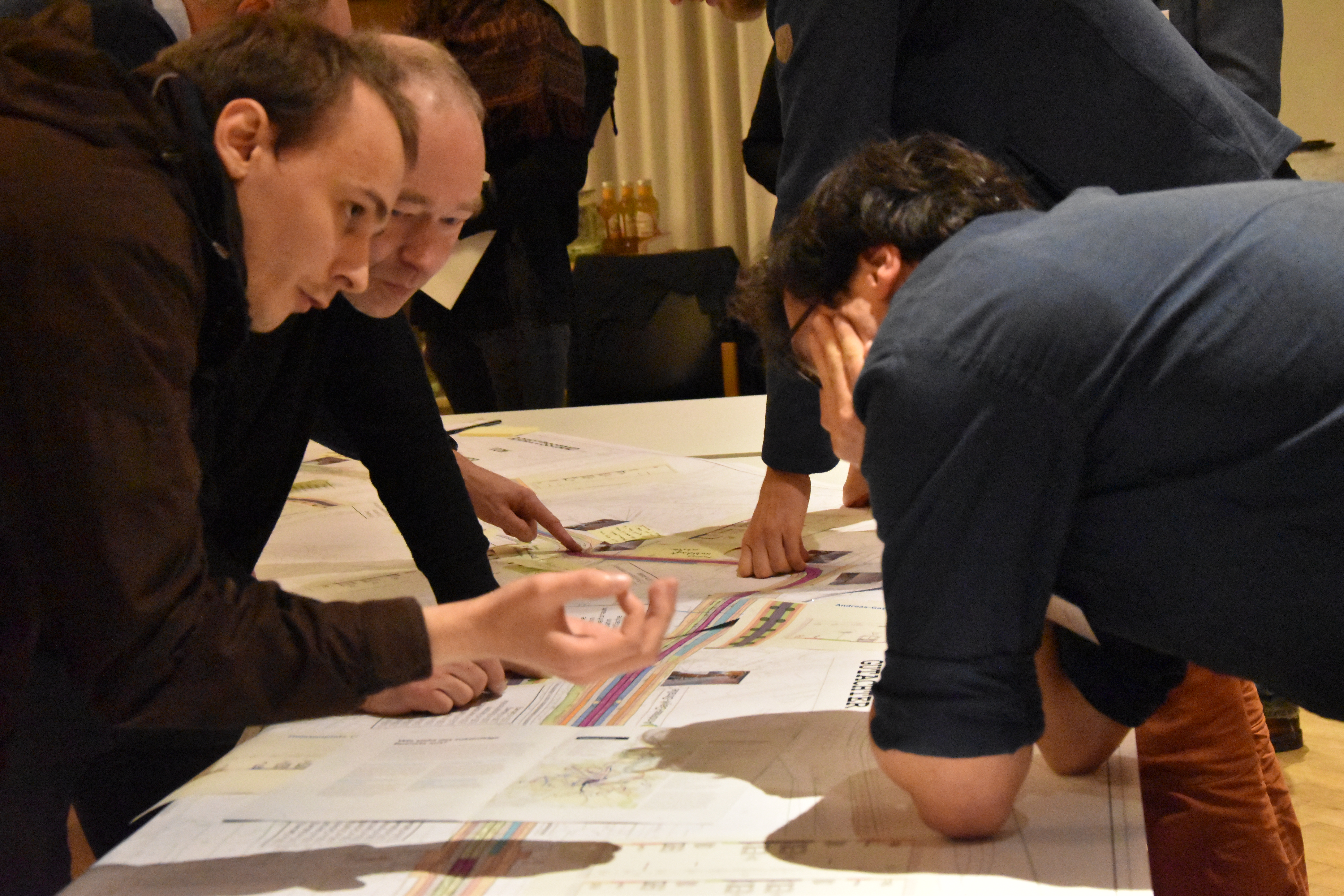 Bürger diskutieren an einem Tisch anhand der Stadtbahn-Pläne