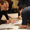 Bürger diskutieren an einem Tisch anhand der Stadtbahn-Pläne